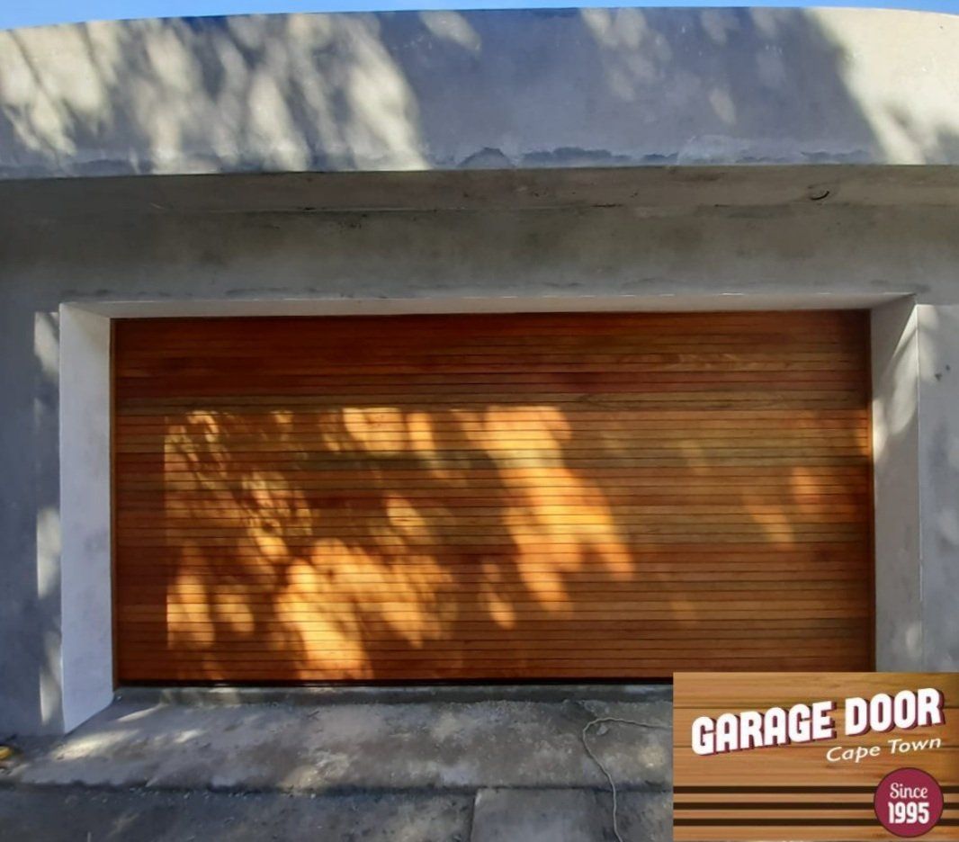 Wooden garage door with sunlit horizontal lines in a gray cement frame.