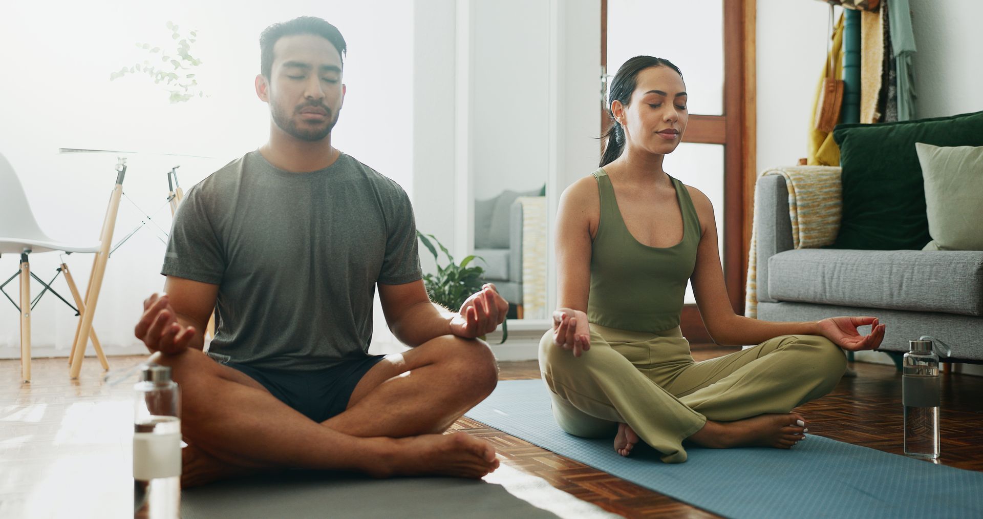 Man and woman in lotus position meditating indoors.