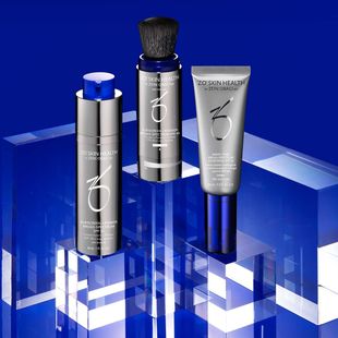 Three silver and blue cosmetic product tubes on a glossy blue geometric background.