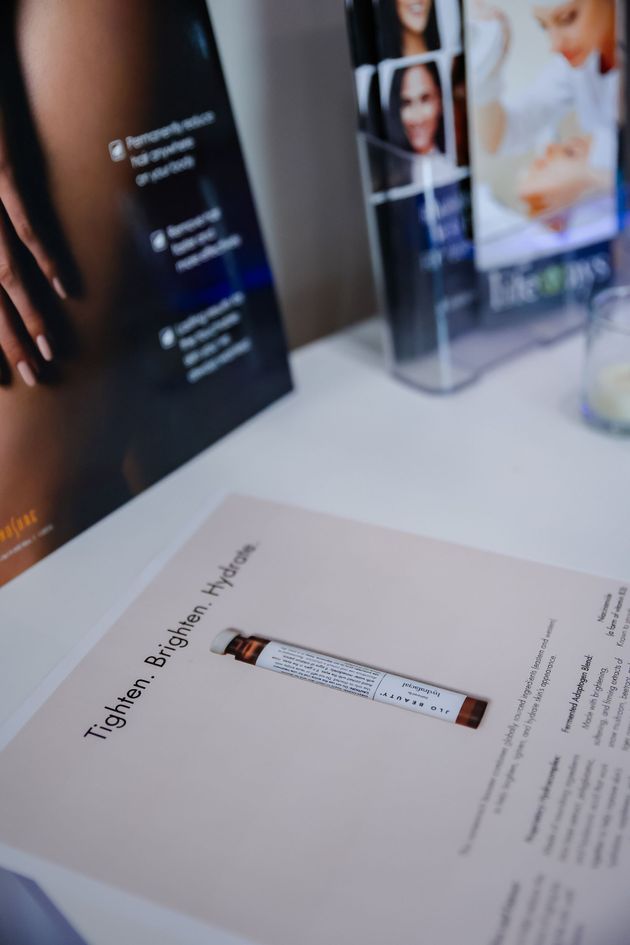 Close-up of a brochure with a microscope image on a white table, with blurred display panels in the background