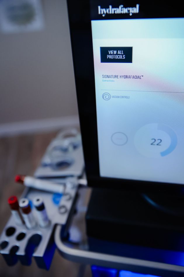 Hand holding a small blue-and-white electronic board beside a monitor displaying a website