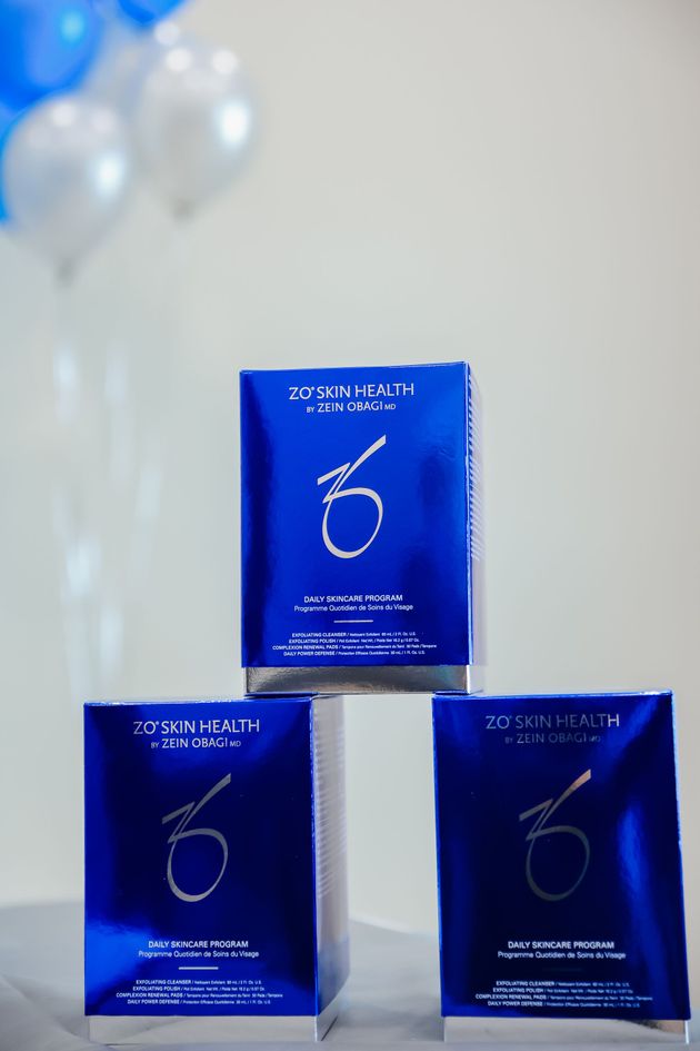 Three blue product packages stacked in a pyramid against a light background with balloons