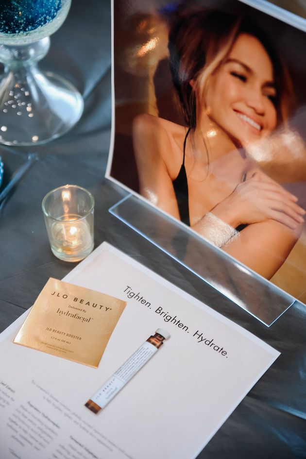 Spa table with a smiling model photo, candle, and brochure on a gray surface