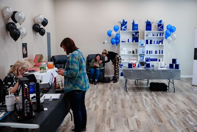 Balloon-decorated event room with people arranging tables, gifts, and blue-and-black decorations