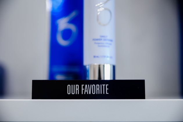 Black sign reading “OUR FAVORITE” before blurred blue and white bottles on a shelf