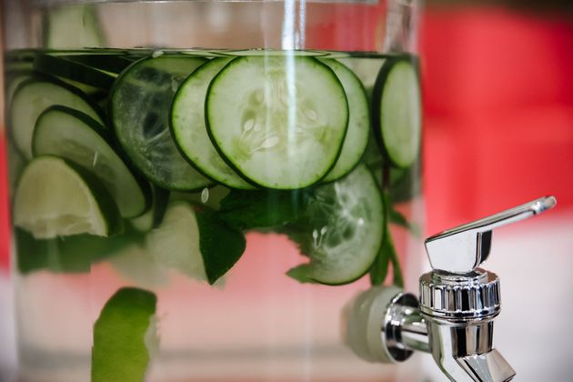 Cucumber slices in water beside a chrome tap, suggesting a fresh spa drink or infusion