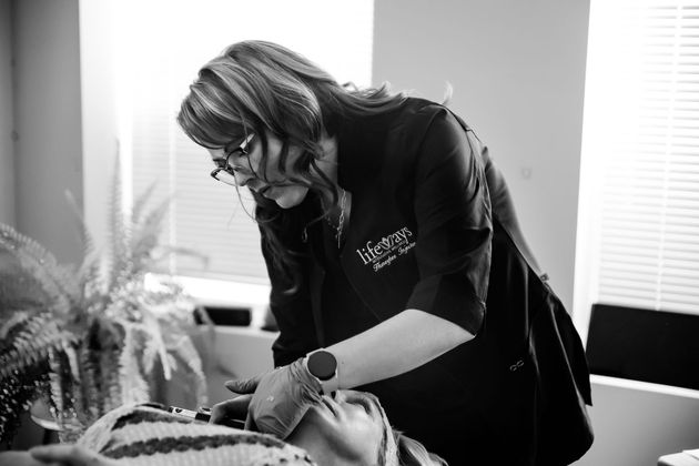 Person leaning over a patient, adjusting medical equipment in a bright clinical room.