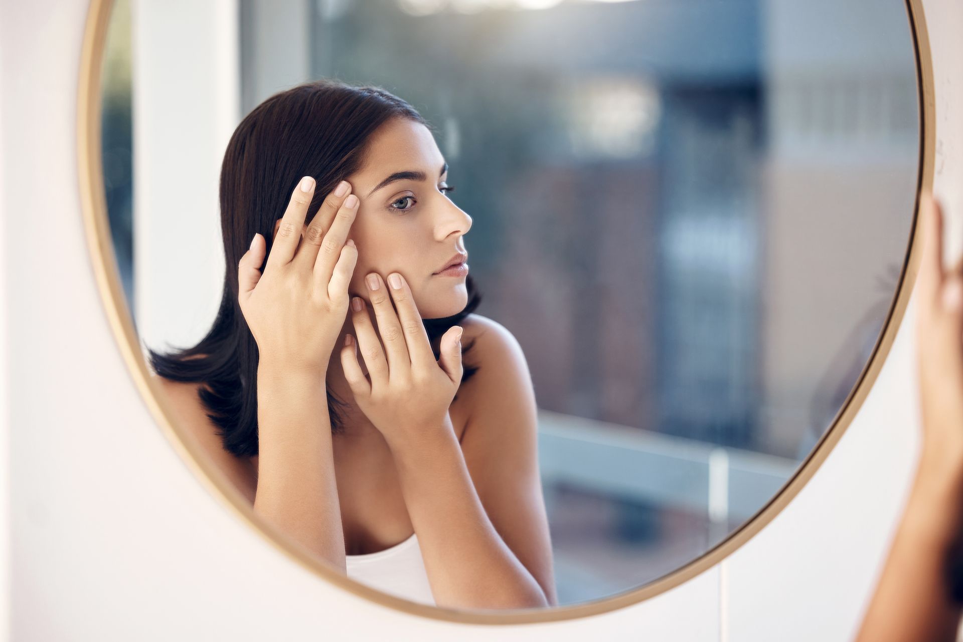 woman looking at skin in mirror