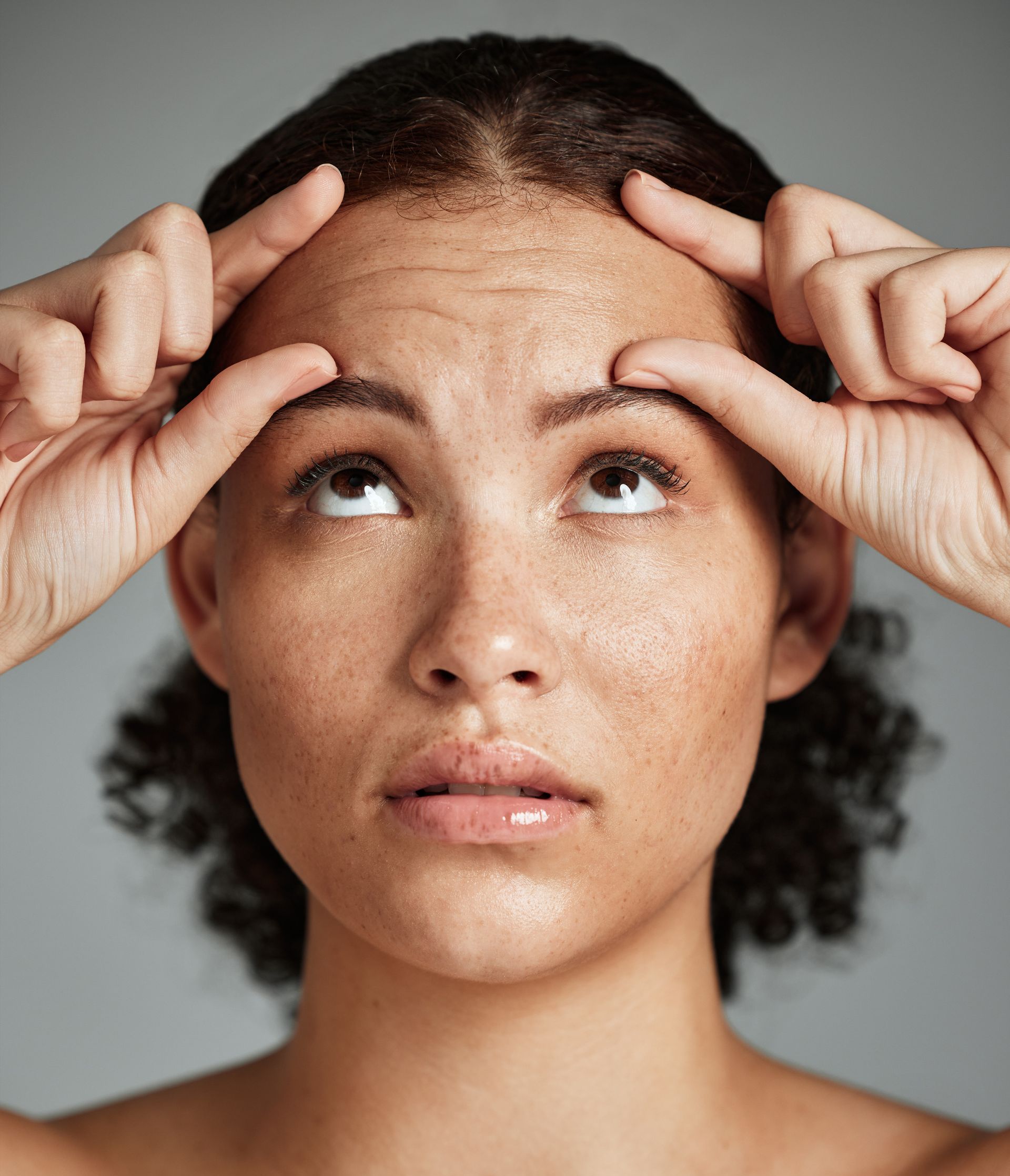 woman looking at wrinkles on forehead
