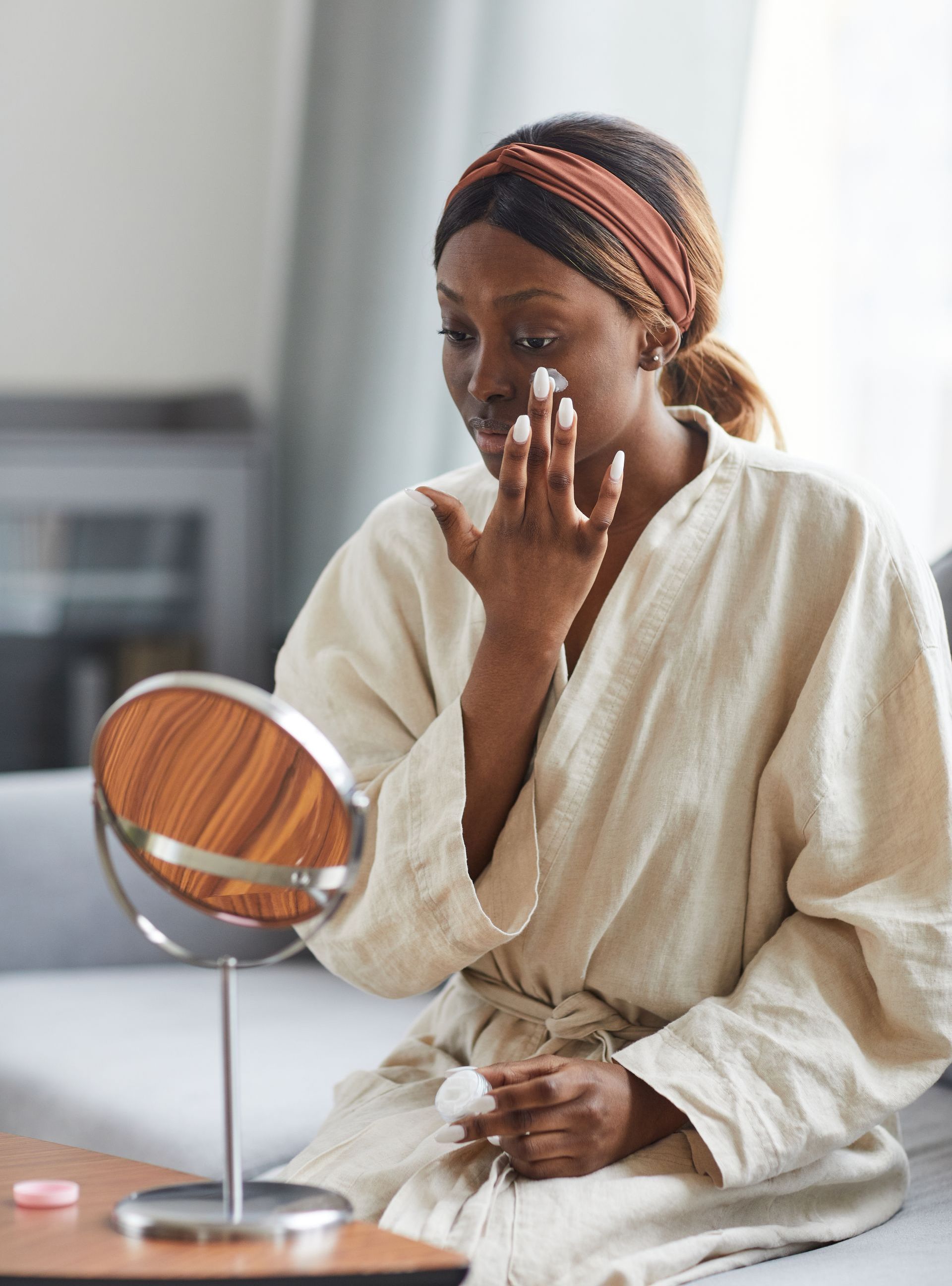 young woman applying moisturizer to skin