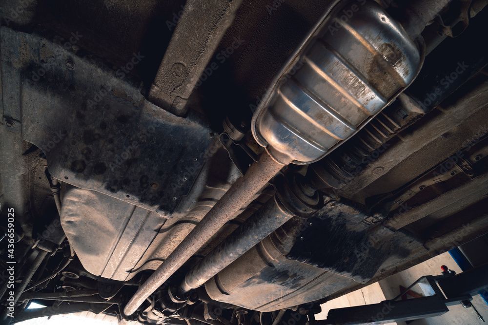 Mechanic using a laptop and diagnostic tool to inspect a car engine in a garage