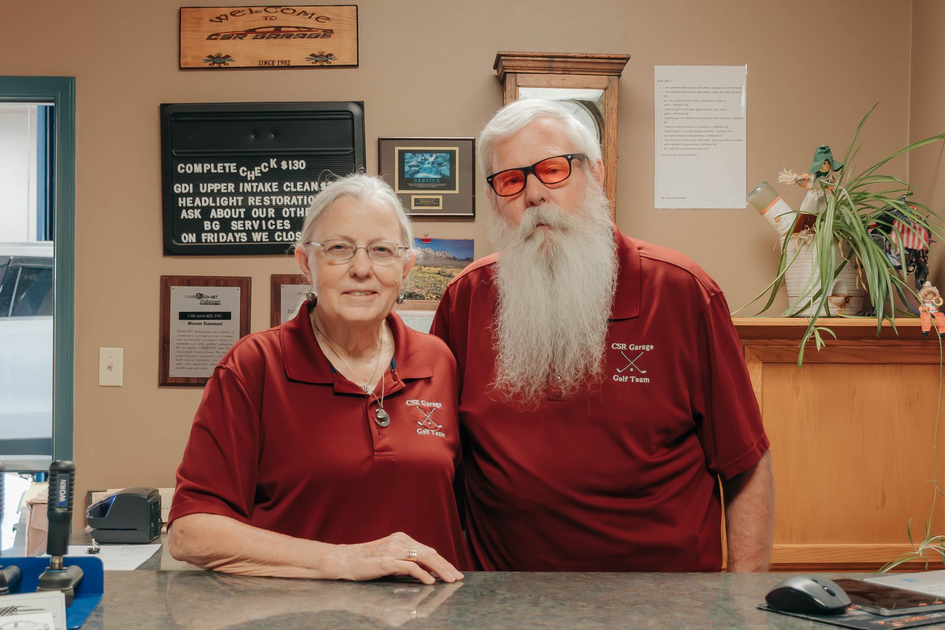 Two staff members in red polos standing behind a reception desk in a lobby