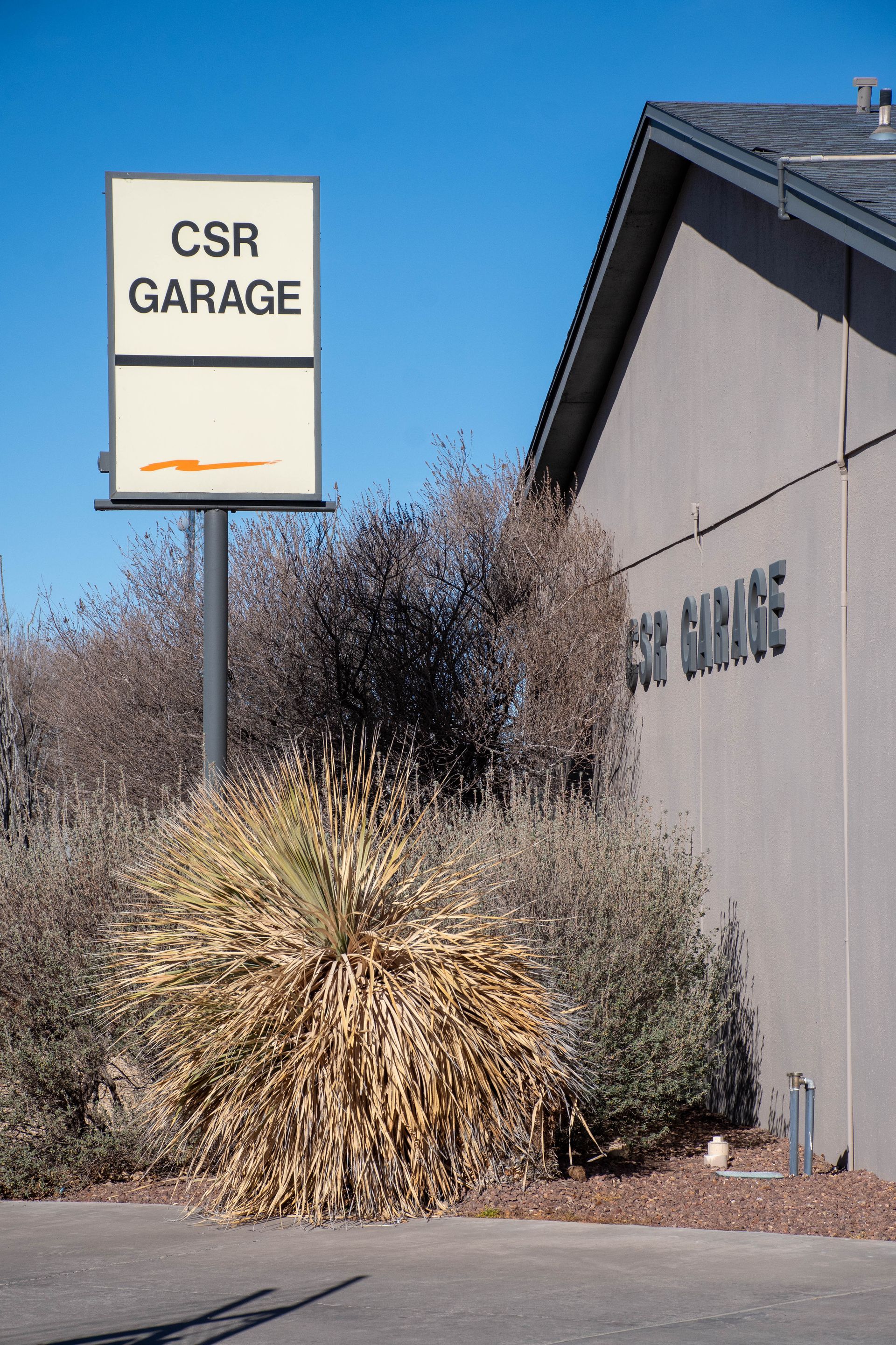 CSR Garage sign beside a beige building and desert shrubs under a clear blue sky