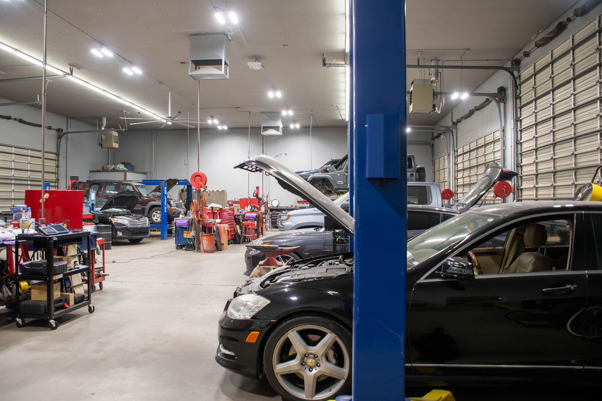 Auto repair shop interior with cars on lifts, tools, and a blue support column
