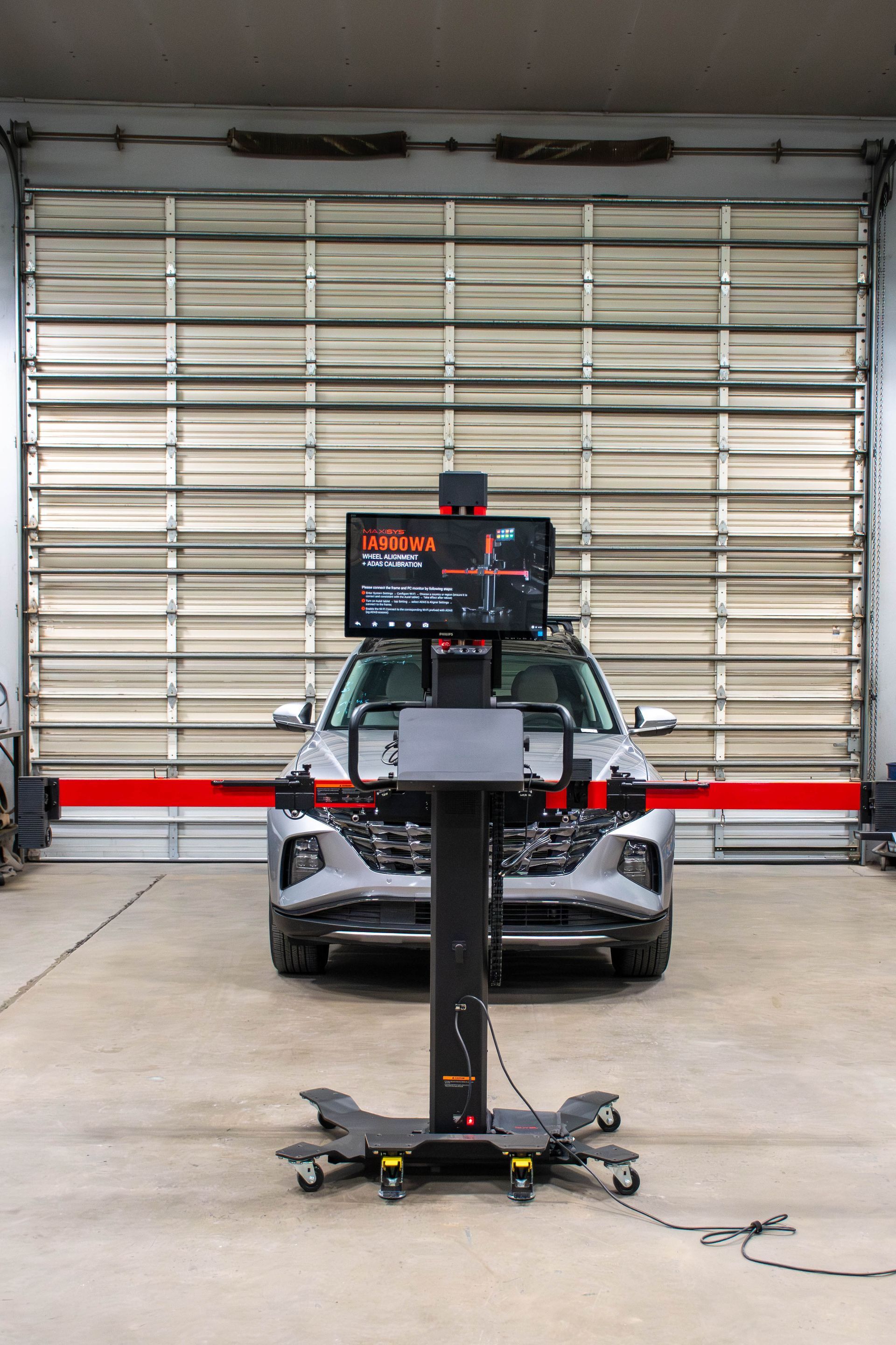 Mobile display cart in a garage, with a car behind it and a large closed roll-up door.
