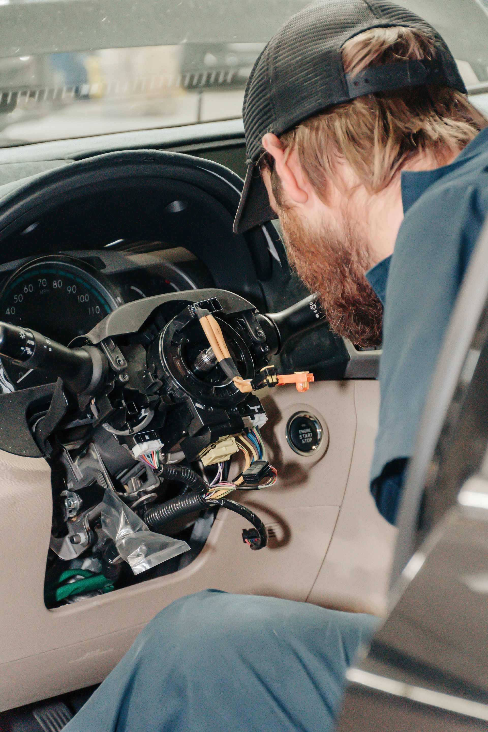Person repairing a car dashboard with exposed wiring inside the driver’s side interior
