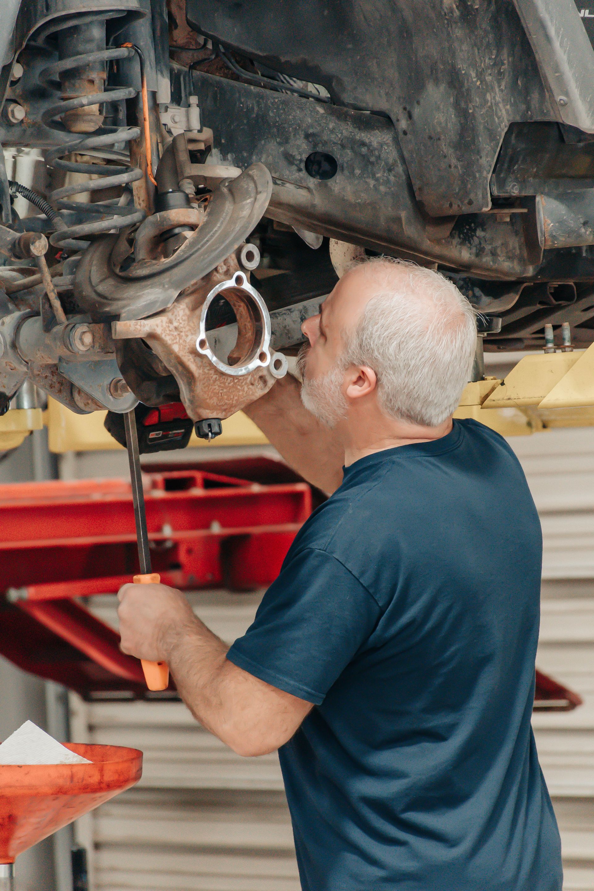 Mechanic inspecting the underside of a car on a lift in an auto shop