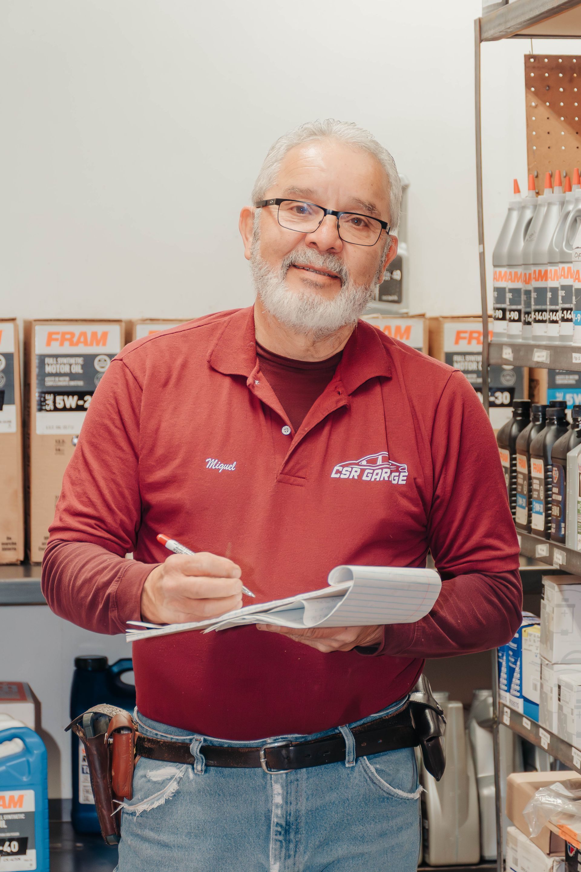 Man in red shirt writing on a clipboard in an auto parts store aisle