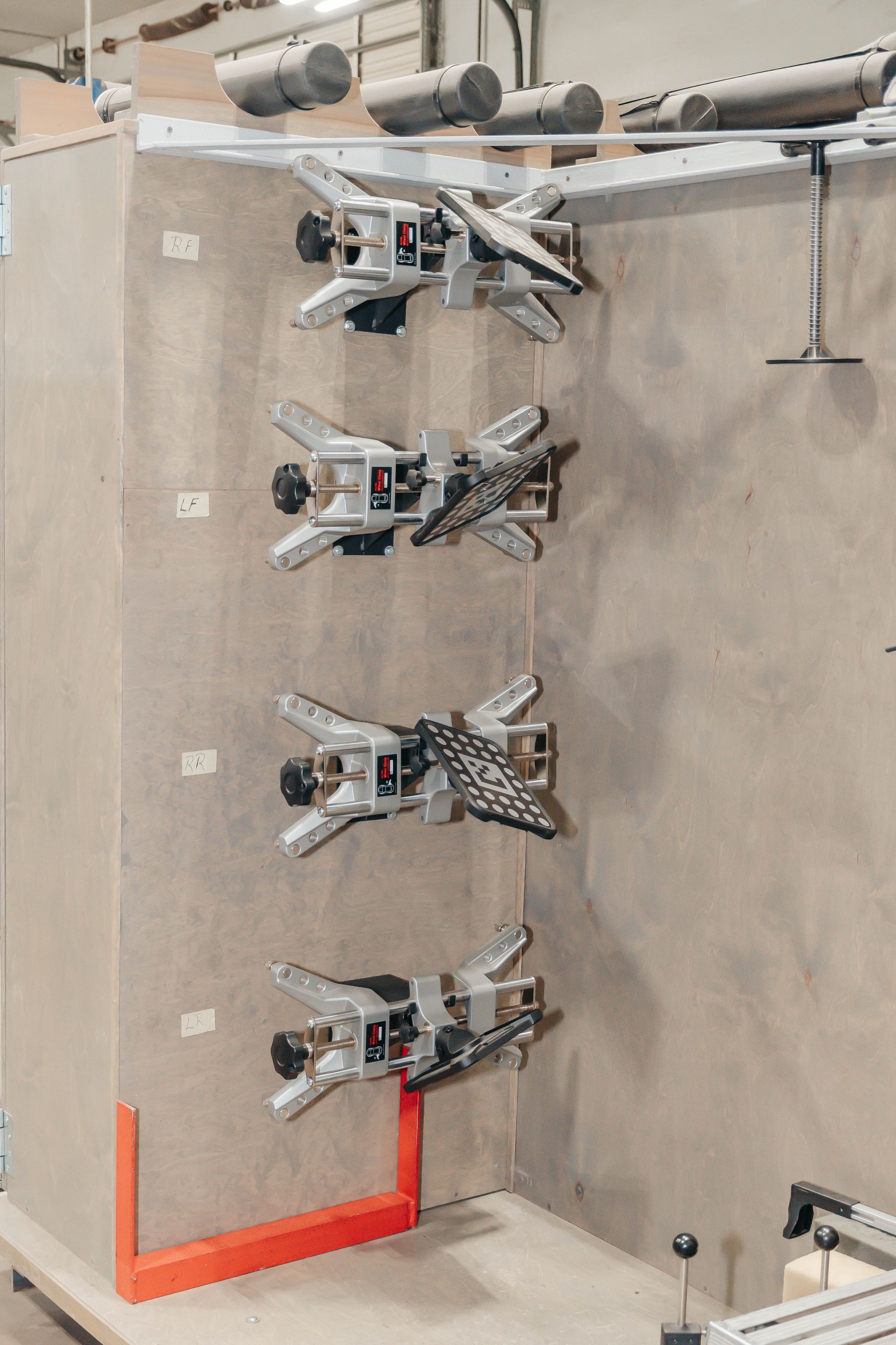Four robotic grippers arranged vertically on a wall-mounted industrial display in a workshop.