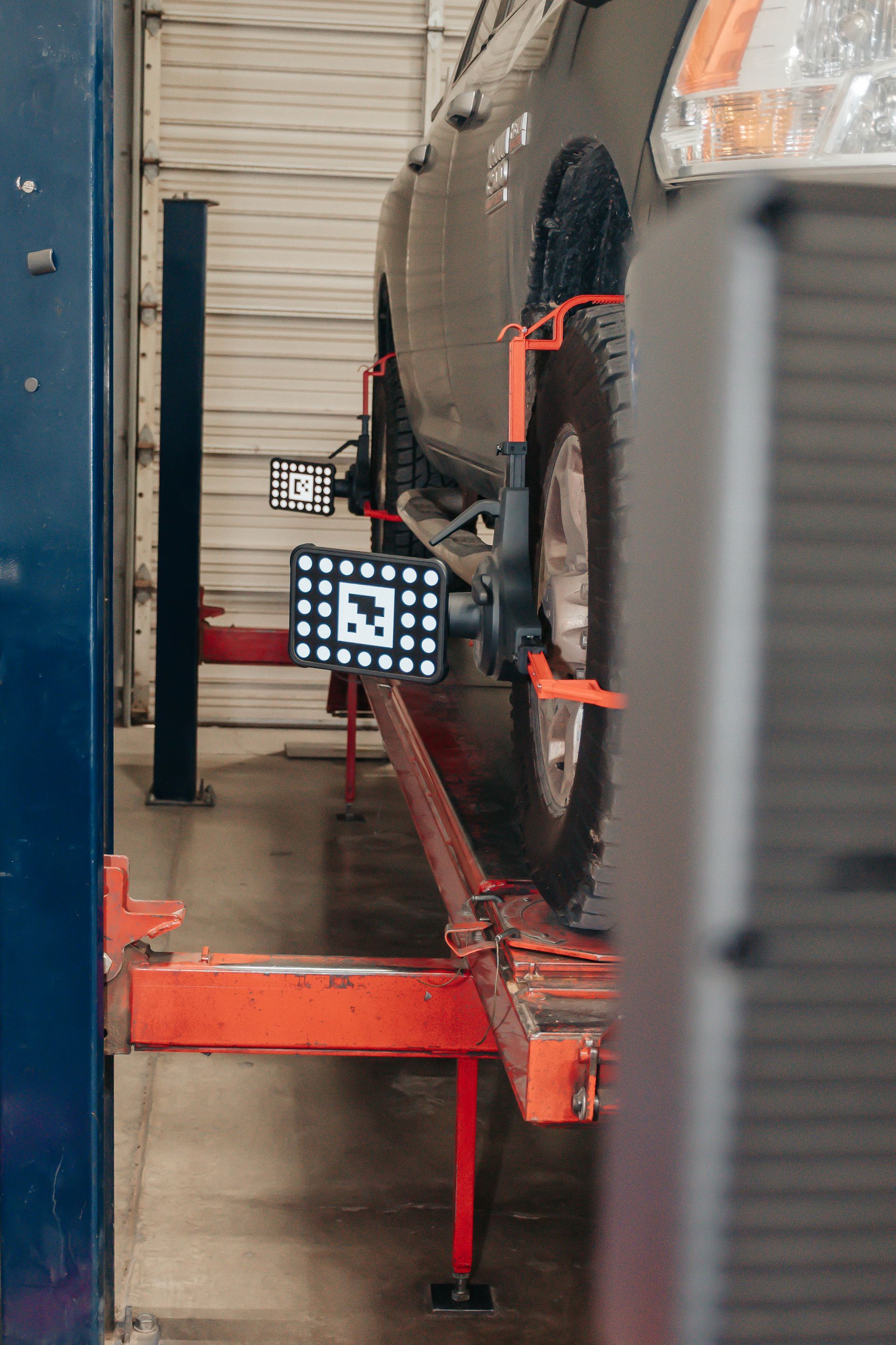 Mechanics working on cars in a bright auto repair shop with hoods open and tires on the wall