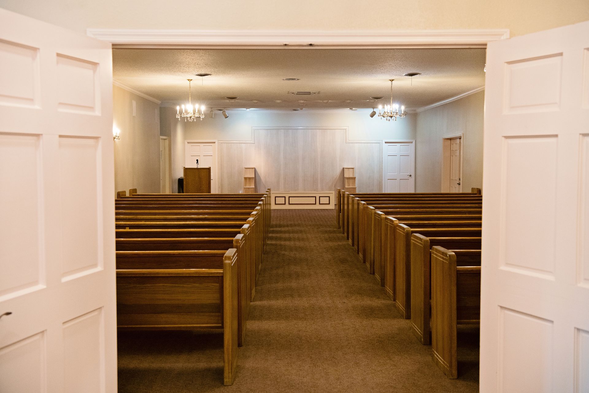 Empty church sanctuary with wooden pews facing a white altar and central aisle