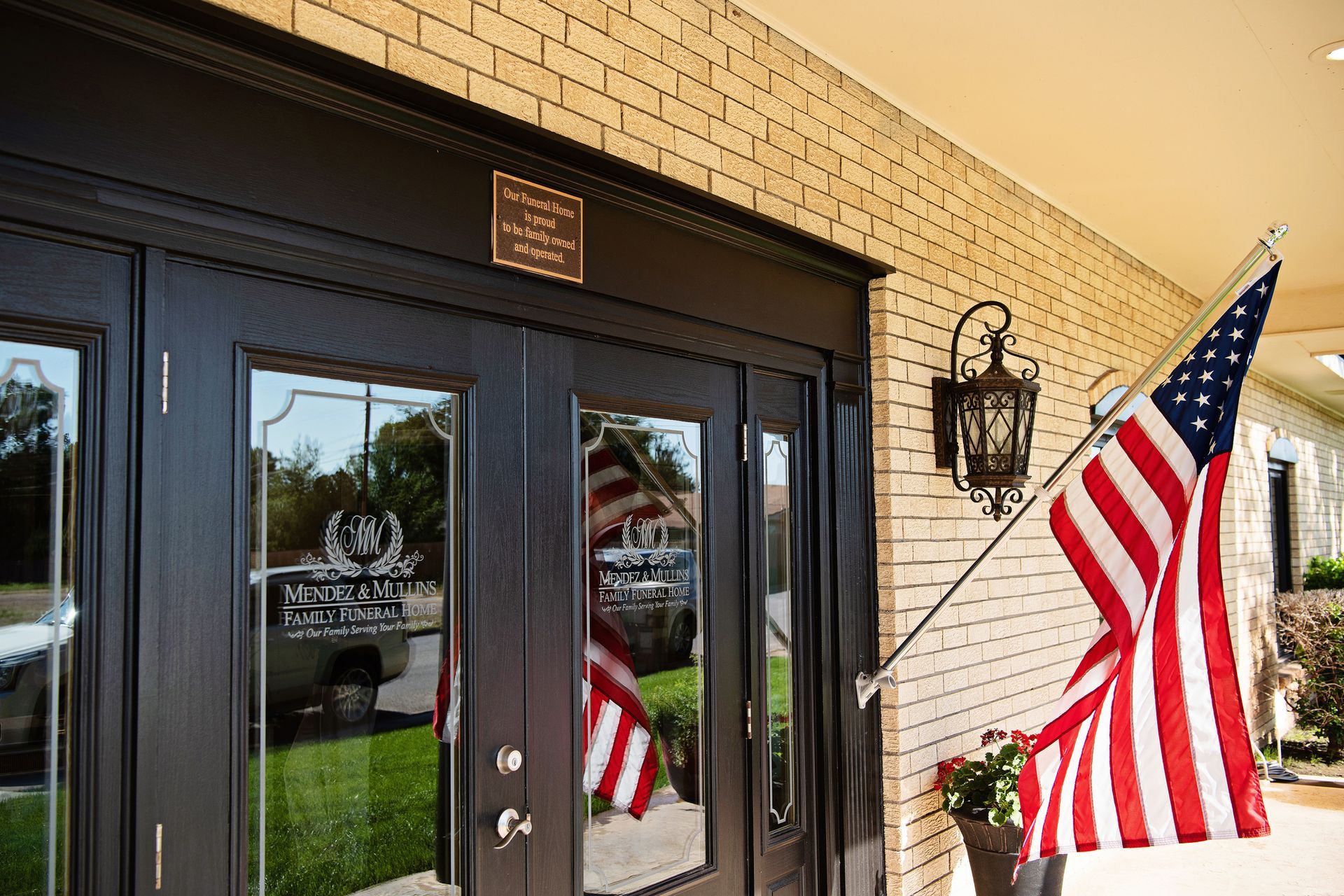 Glass storefront doors with American flags and brick exterior wall