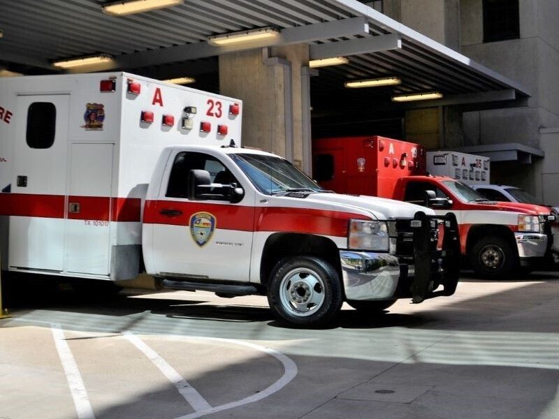 Two red-and-white ambulances parked in a garage, front one labeled 23.