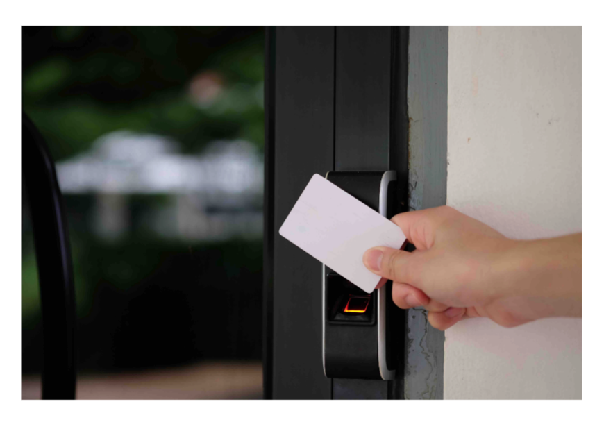 A person is holding a card in front of a door lock.