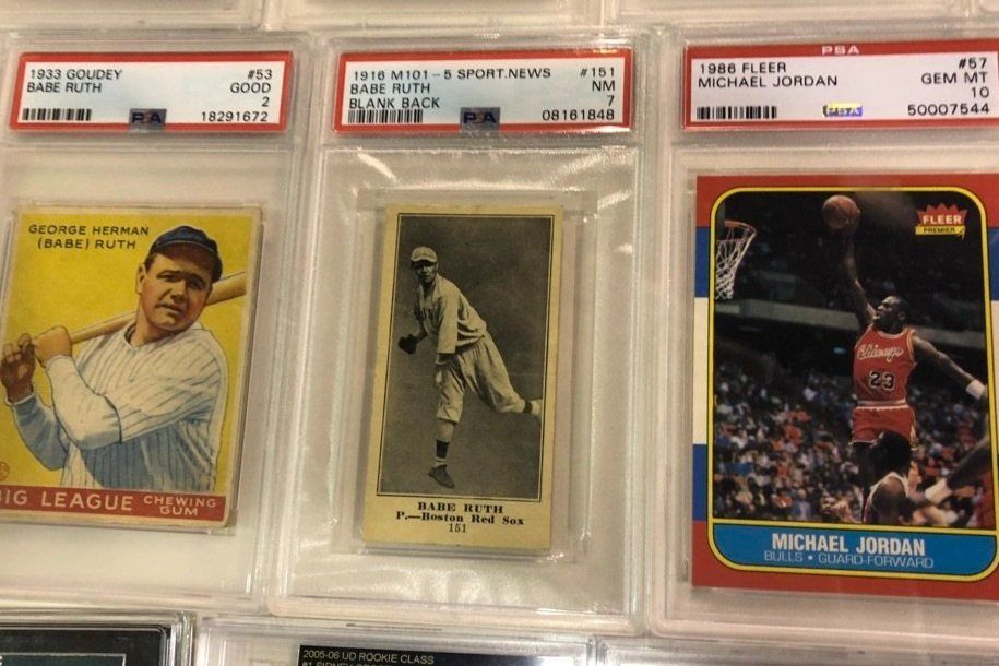 Three baseball/basketball cards in protective cases: Babe Ruth (1933), Babe Ruth (1921), Michael Jordan (1986).