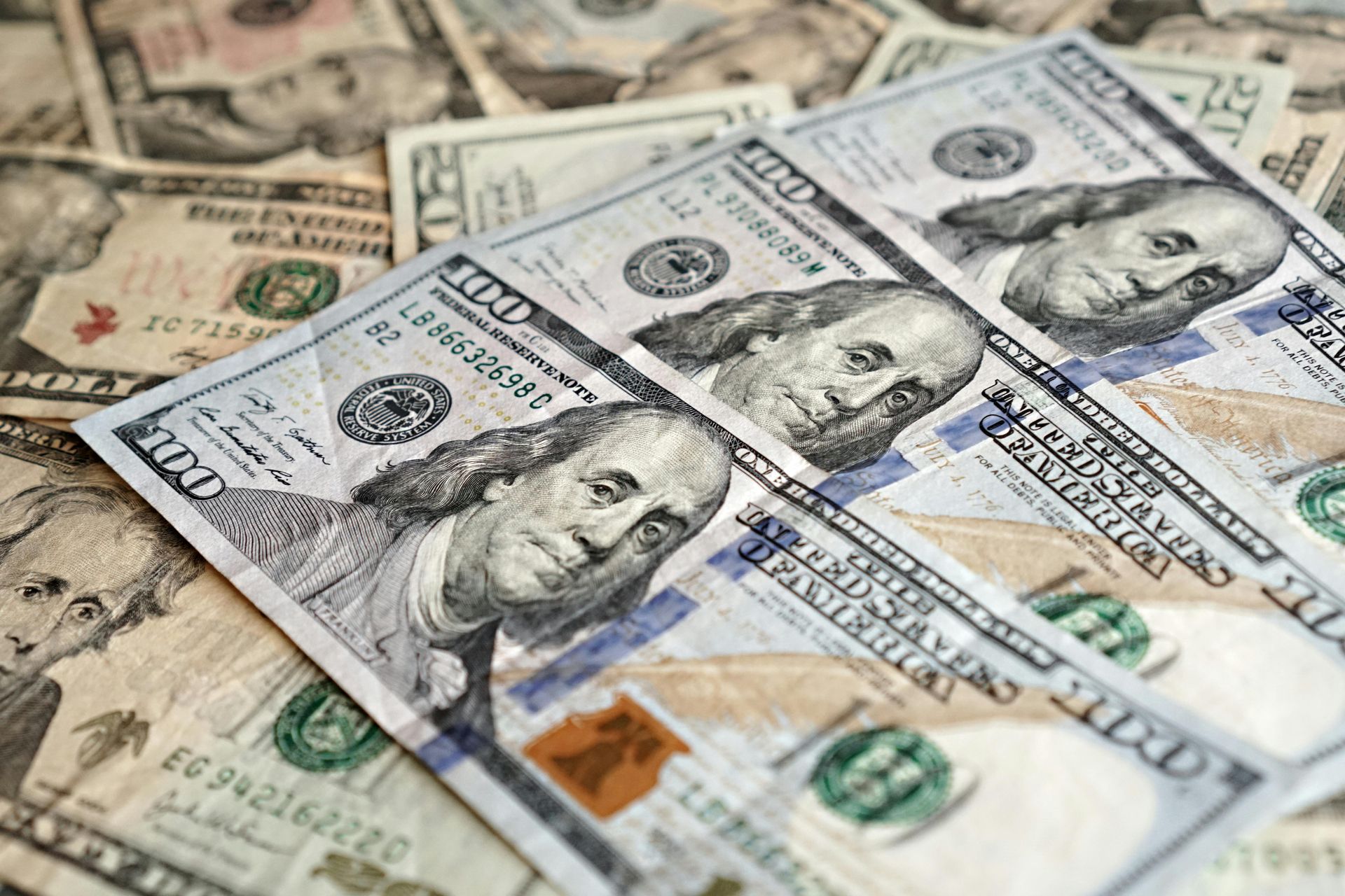A close-up of a pile of scattered US hundred-dollar bills.