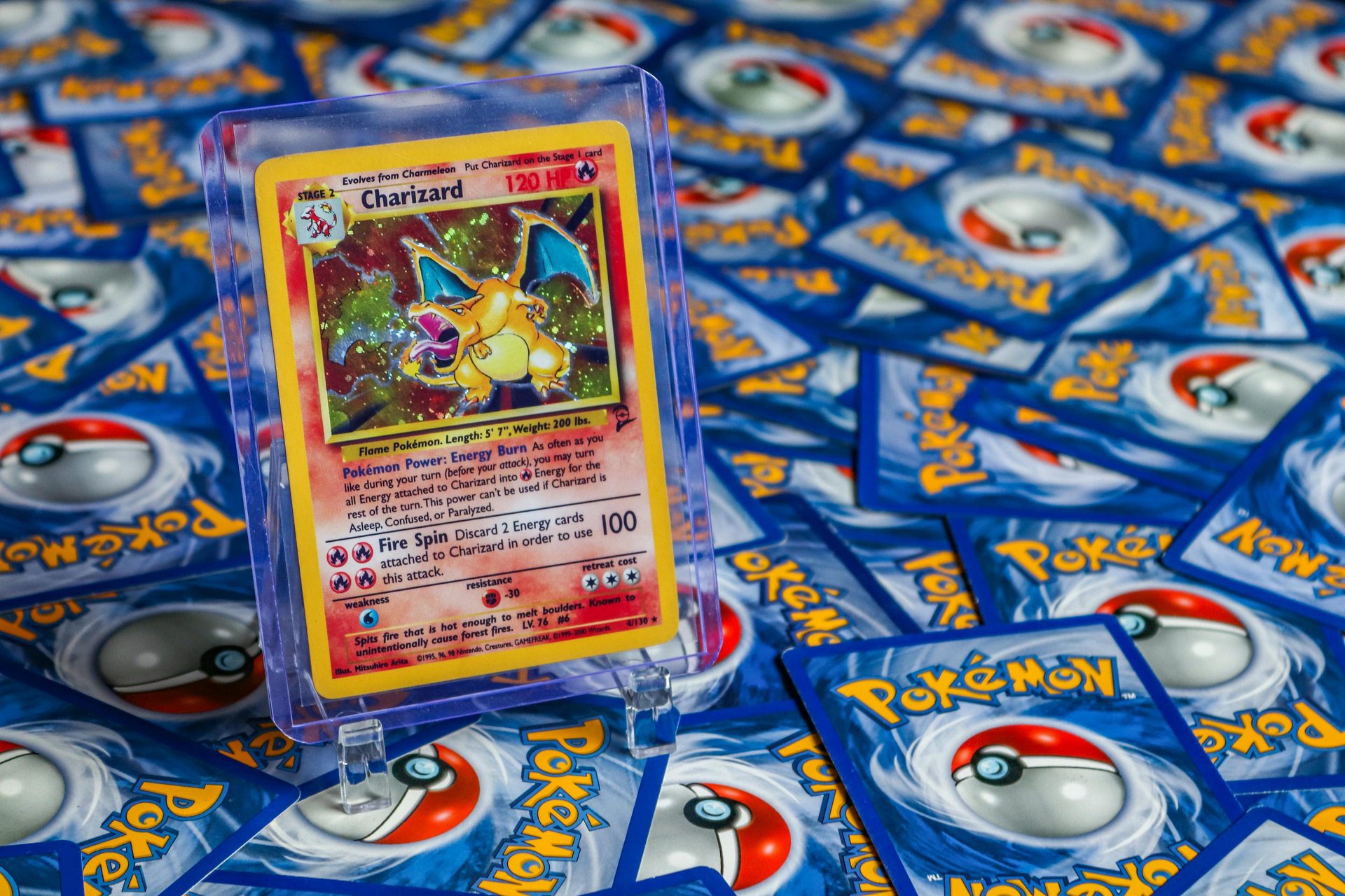 Charizard Pokémon card in a purple sleeve standing on a Pokémon card-patterned background
