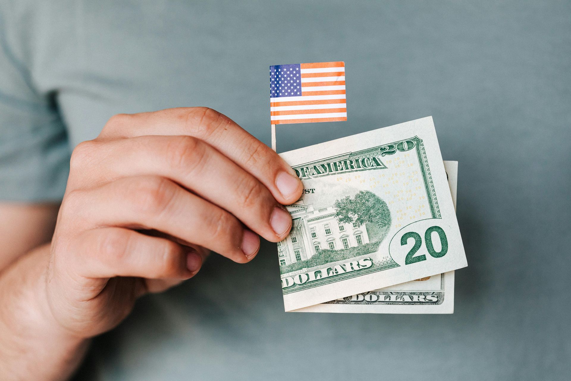 Person holding US dollar bills with a small American flag.