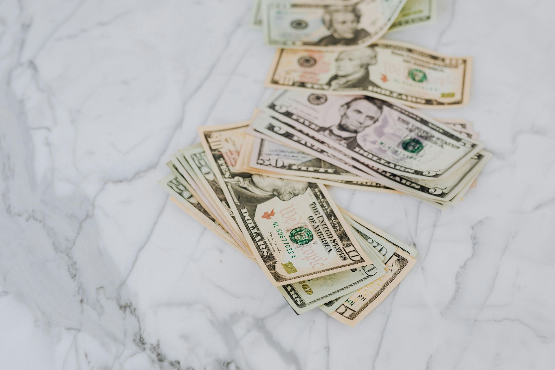 Stacks of US dollar bills on a white marbled surface.