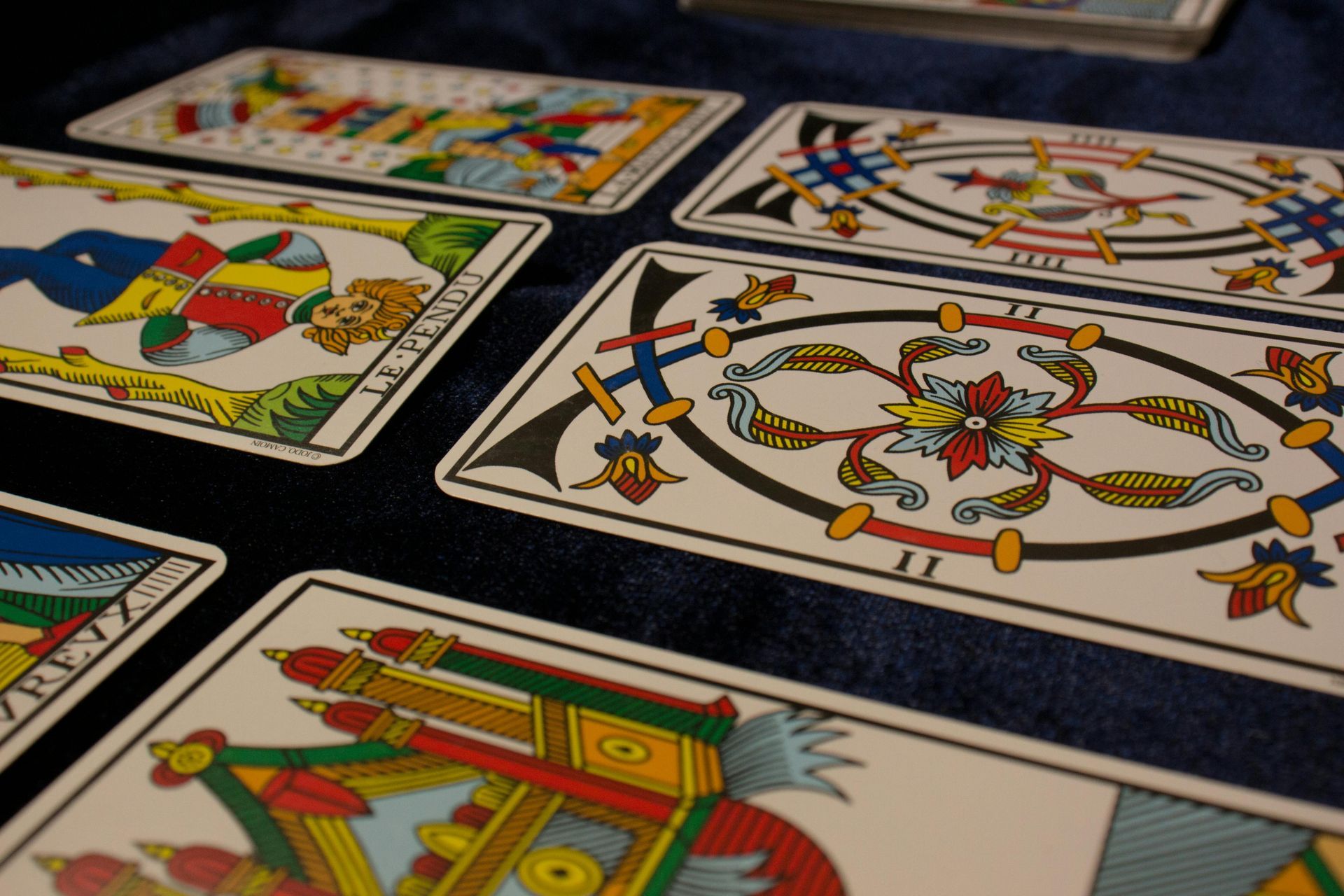 Close-up of tarot cards spread out on a blue cloth, featuring colorful illustrations and ornate designs.