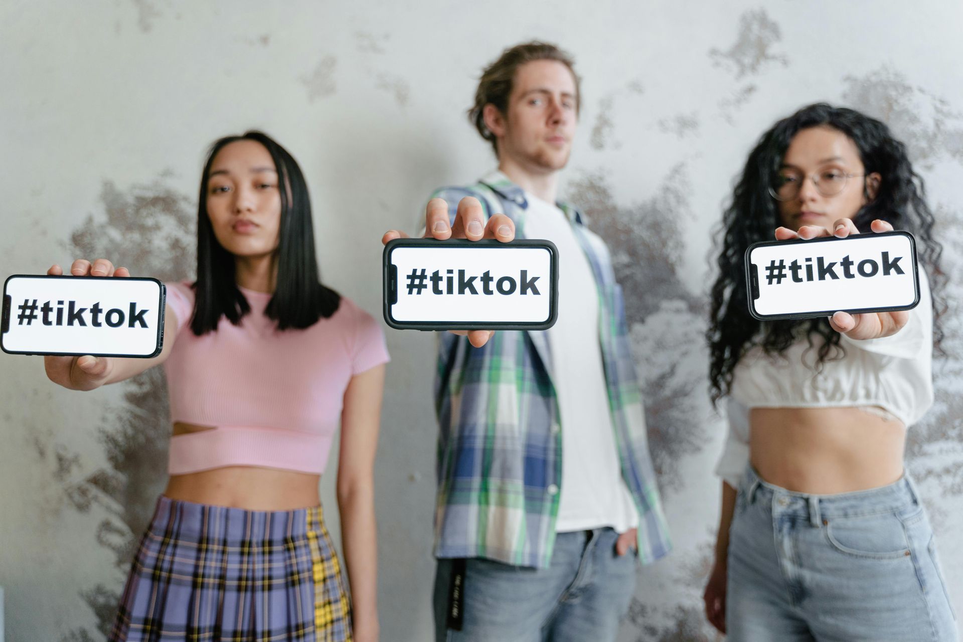 Three people holding phones with 