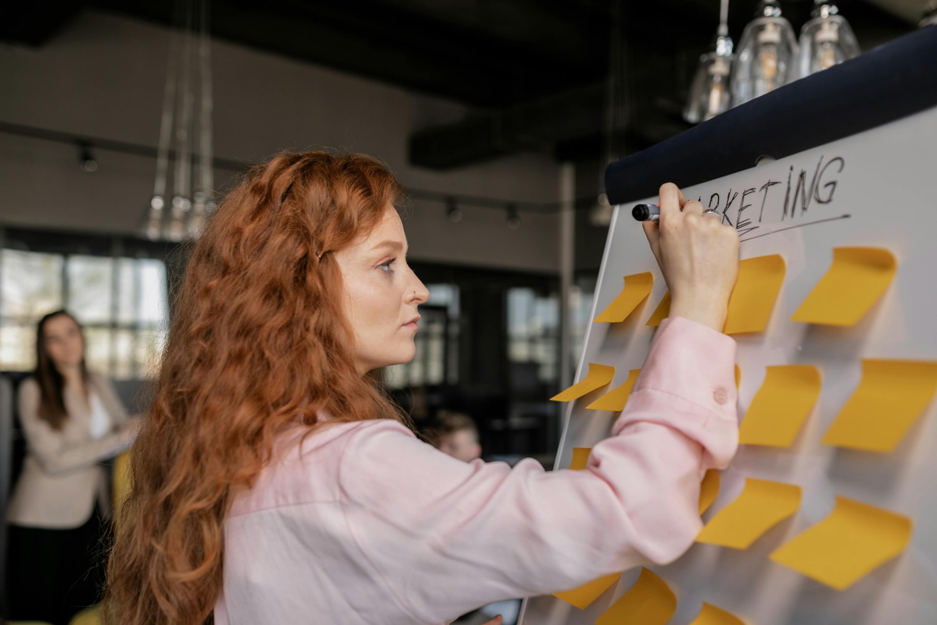 A person with long red hair writing