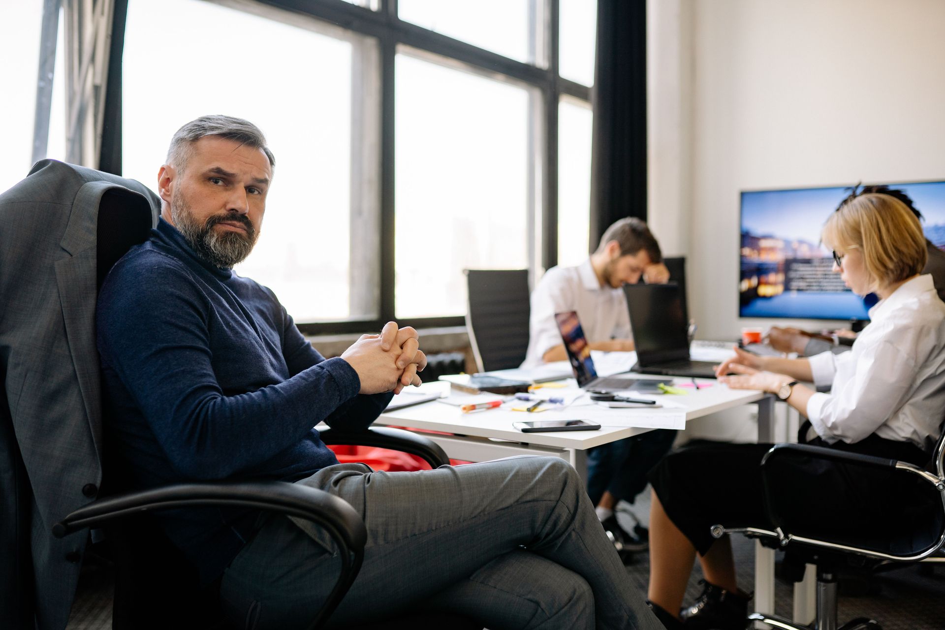 People collaborating at desks in a modern office, with one person looking toward the camera.