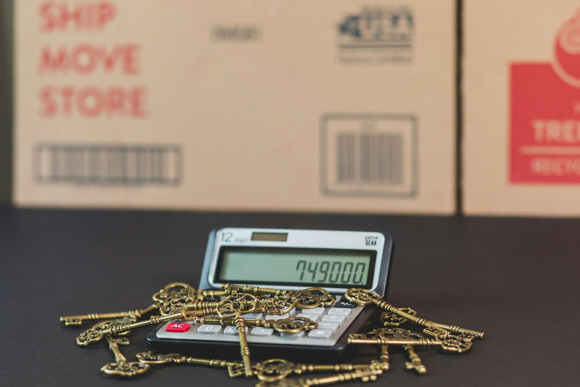 Gold chains piled around a digital scale with a 749.000 reading, in front of moving boxes.