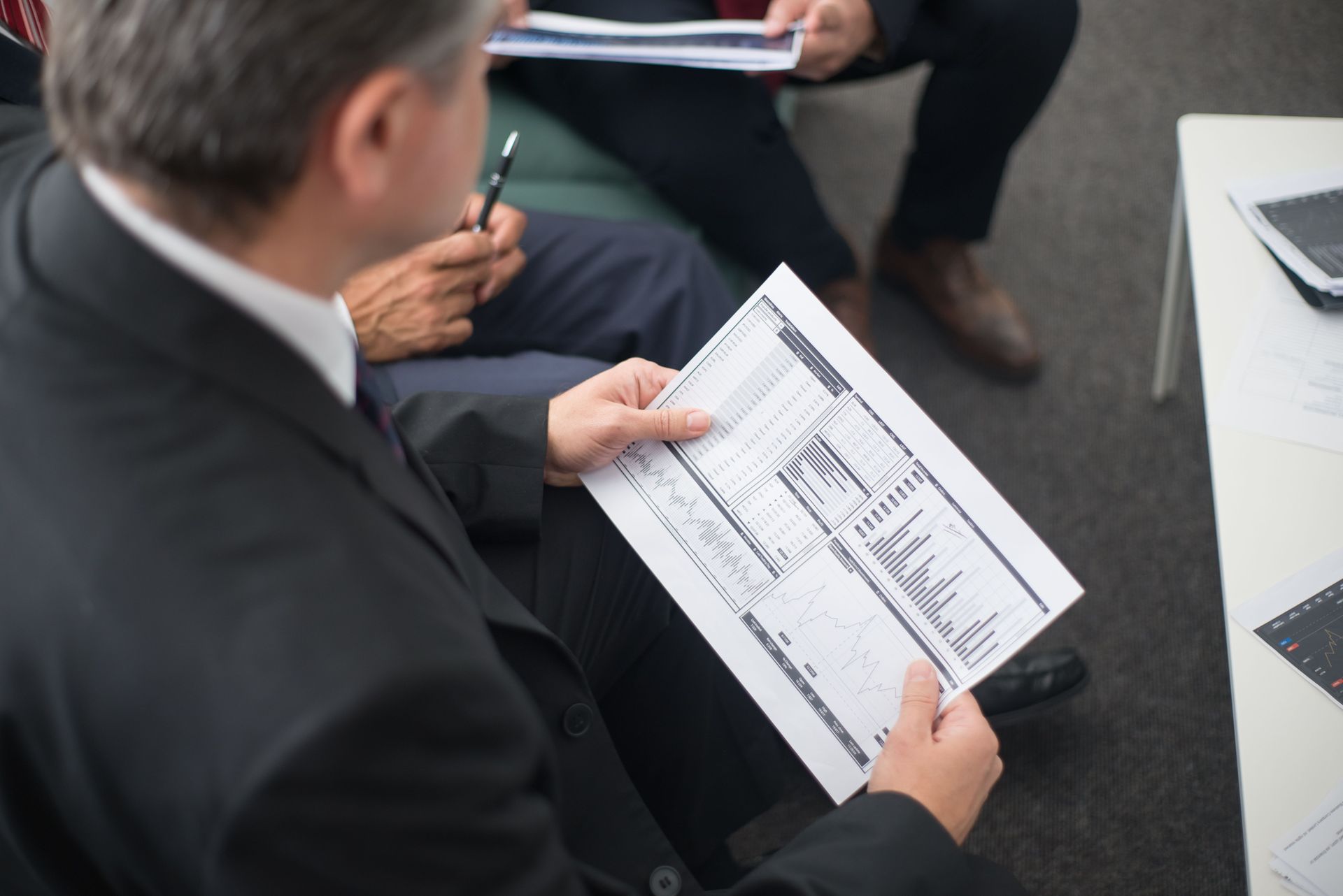 Person reviewing a document during a meeting at a table with laptop and notepad
