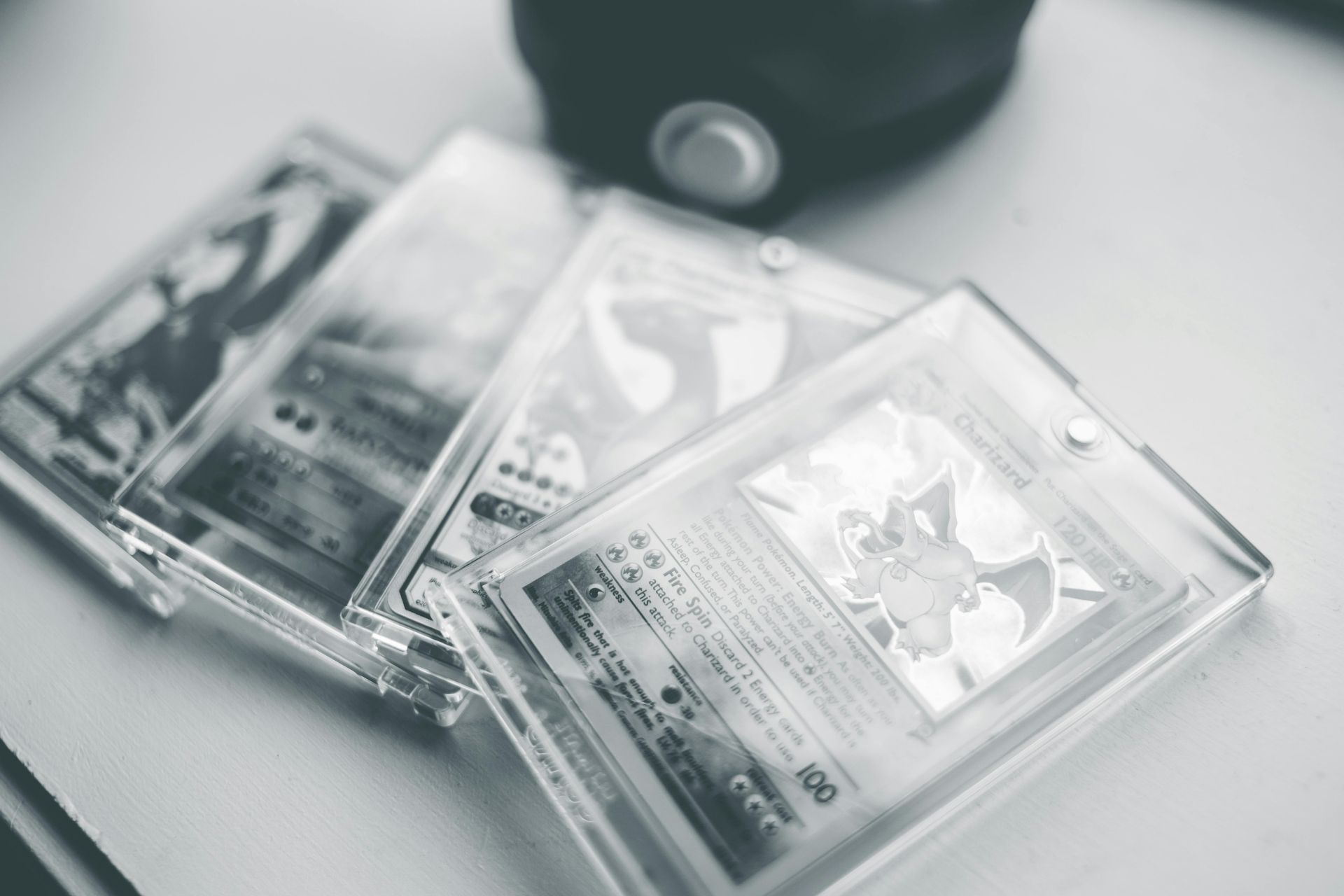 Four Pokémon trading cards in clear protective cases.