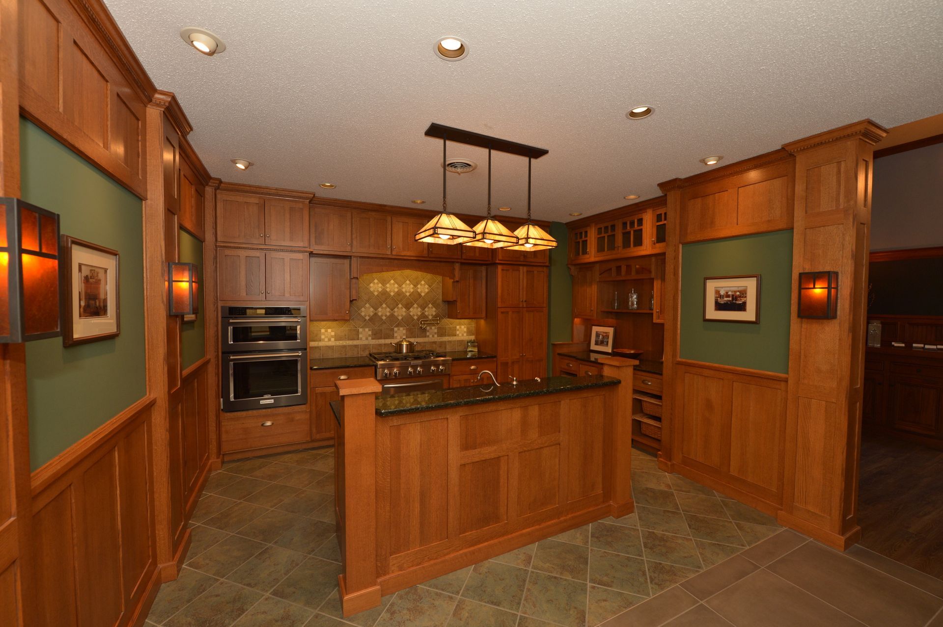 Warm wood kitchen with central island, hanging lights, and built-in appliances
