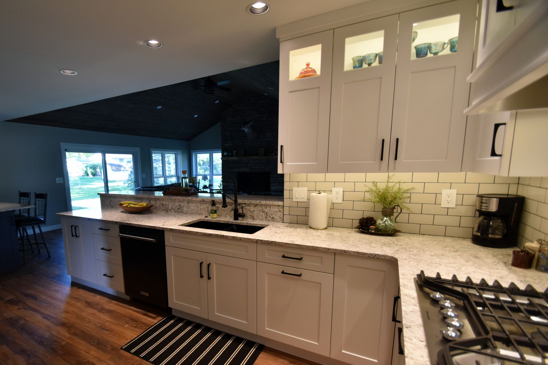 Modern white kitchen with black countertops, tile backsplash, and stainless-steel stove in a contemporary home.