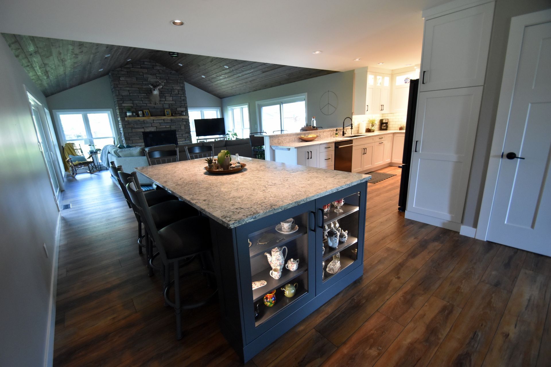 Spacious modern kitchen with a large island, granite countertops, dark wood floors, and stone fireplace.
