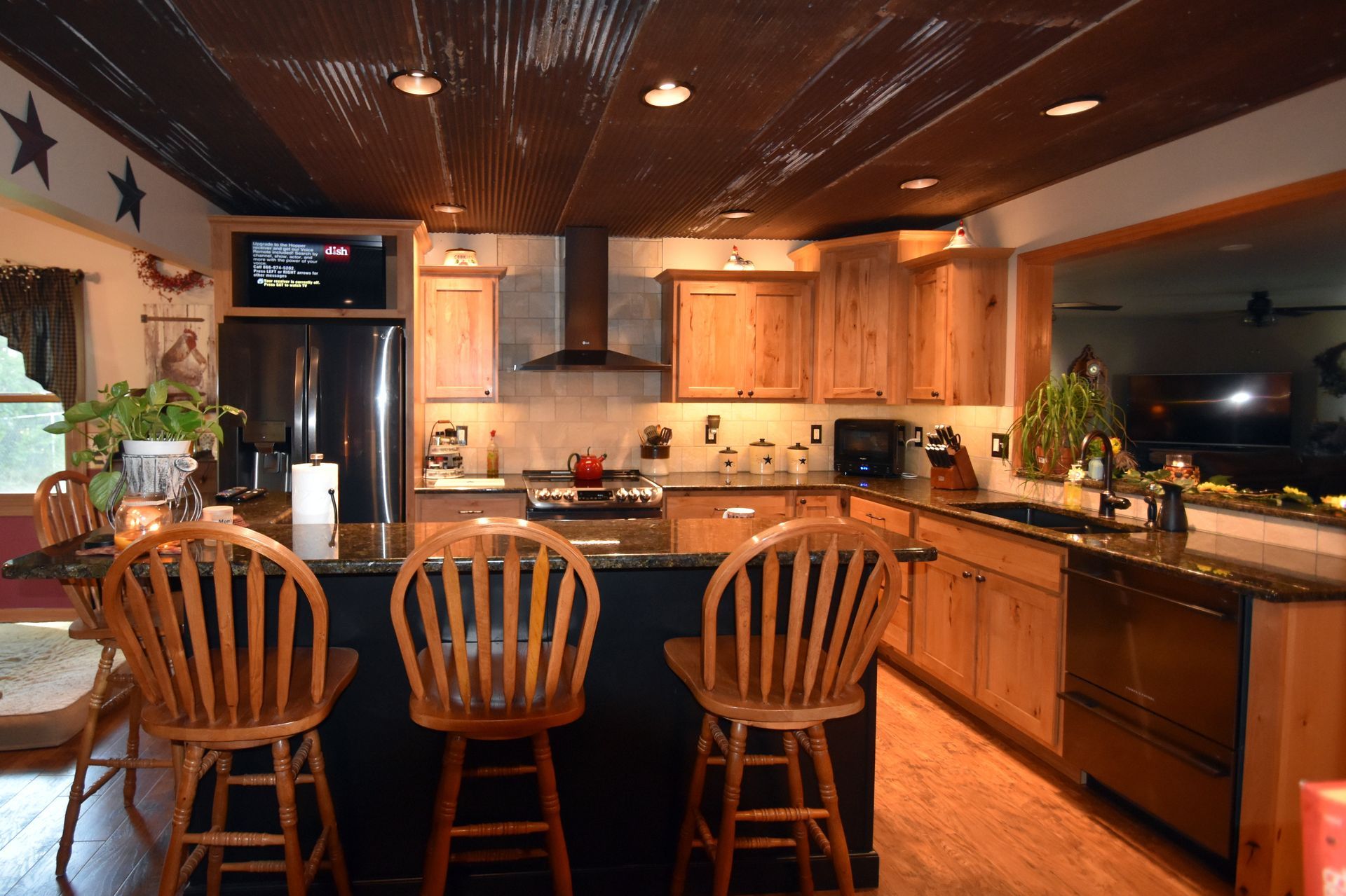 Warm kitchen with wooden bar stools, stainless fridge, and lit countertops in a cozy home interior.