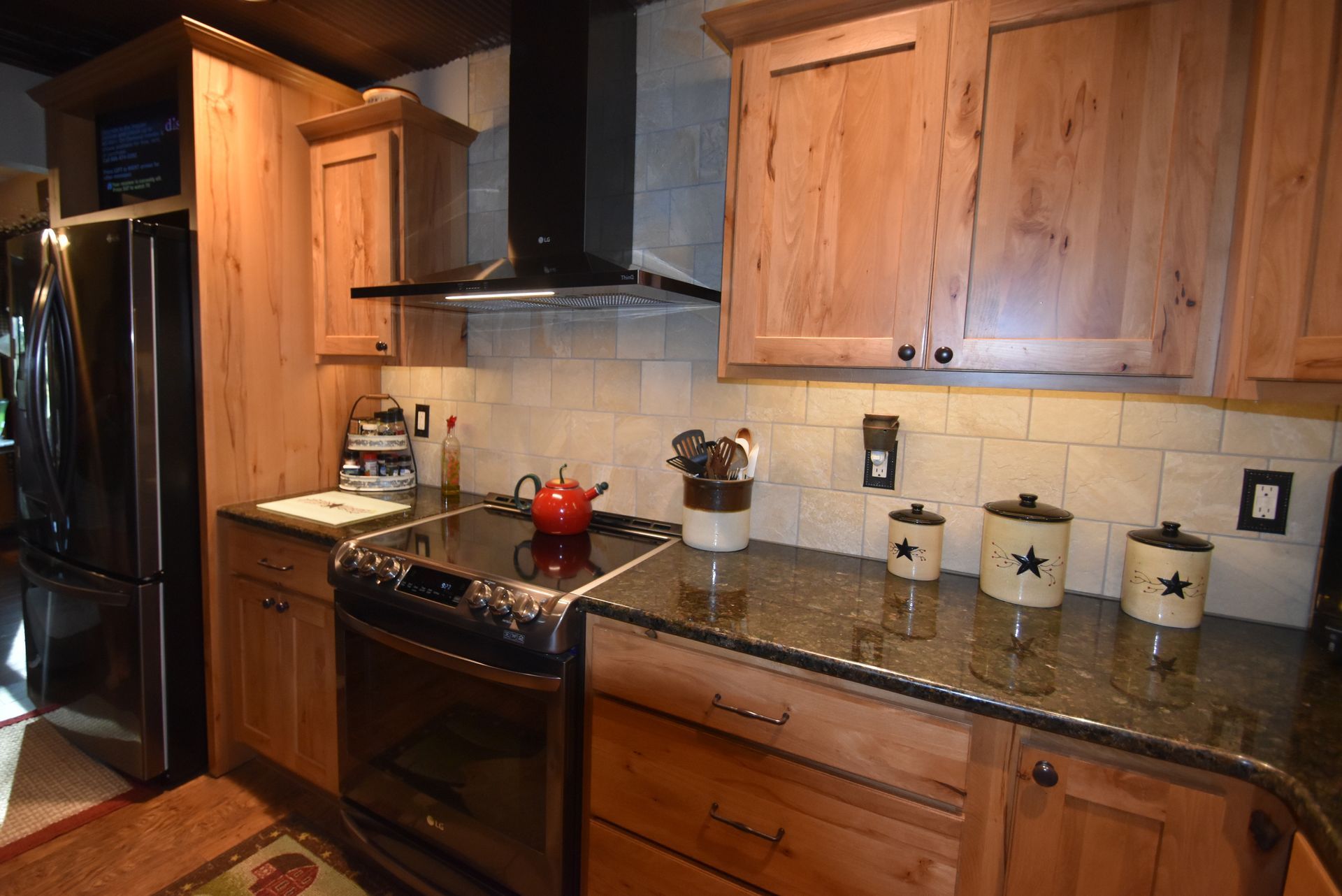 Kitchen with wooden cabinets, granite countertops, stainless stove, and black refrigerator