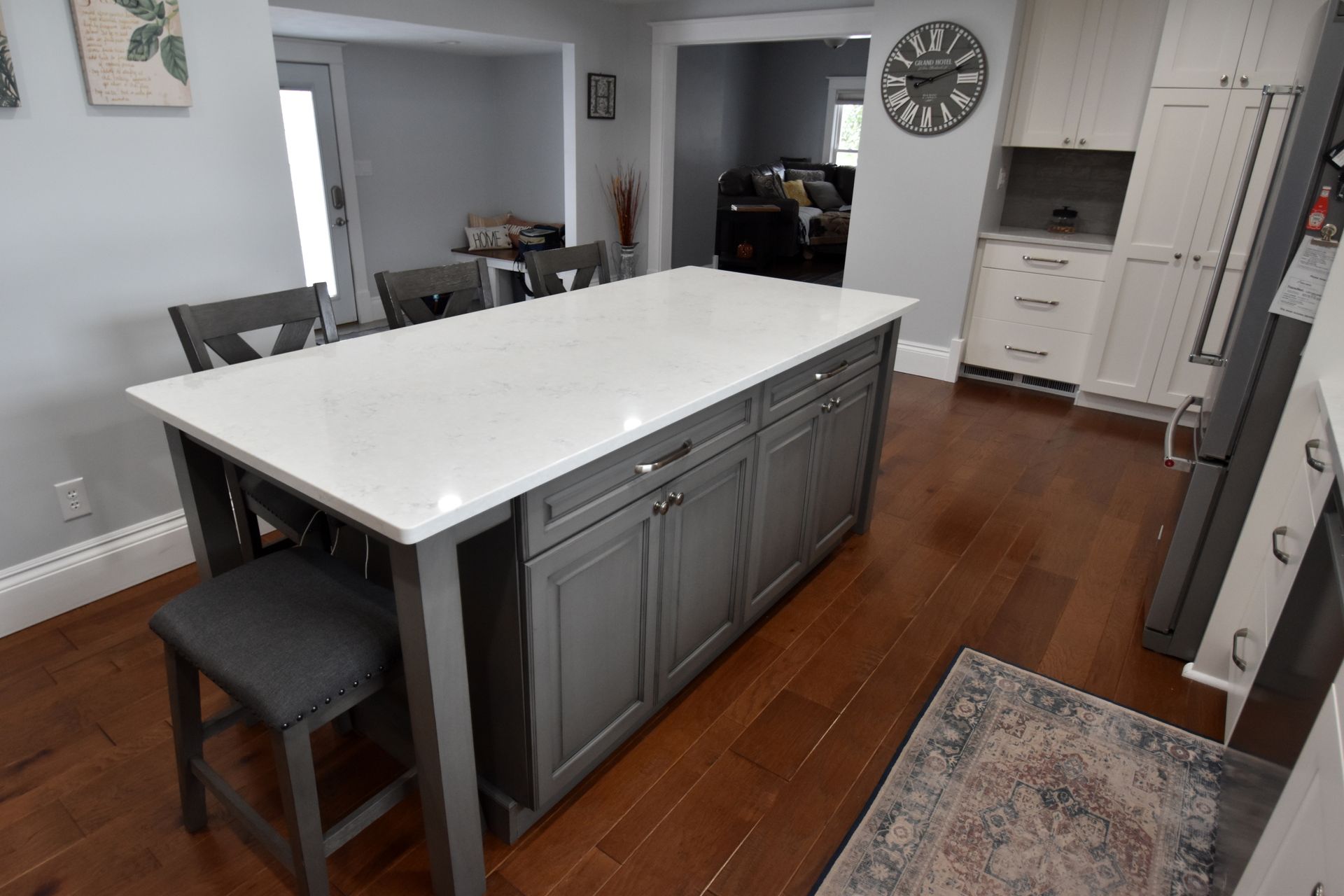Modern kitchen with large island, white countertop, gray cabinets, and hardwood floors