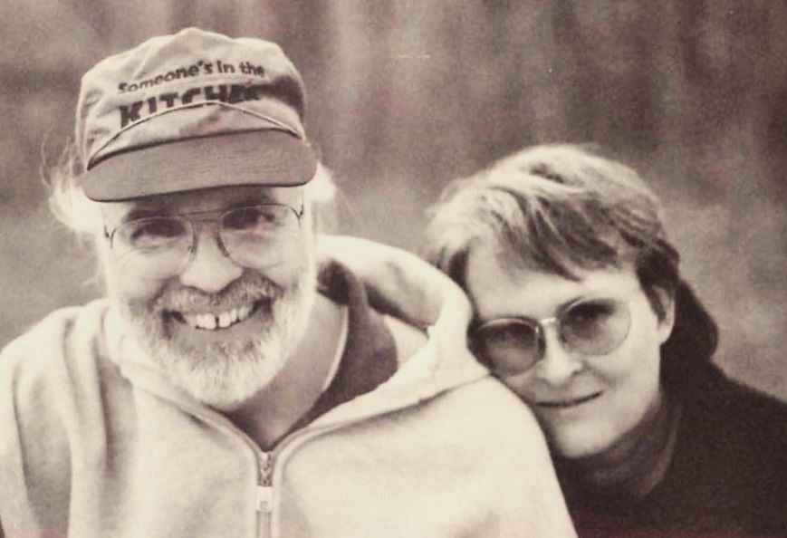 Two smiling people in hoodies and glasses posing outdoors in a sepia-toned photo