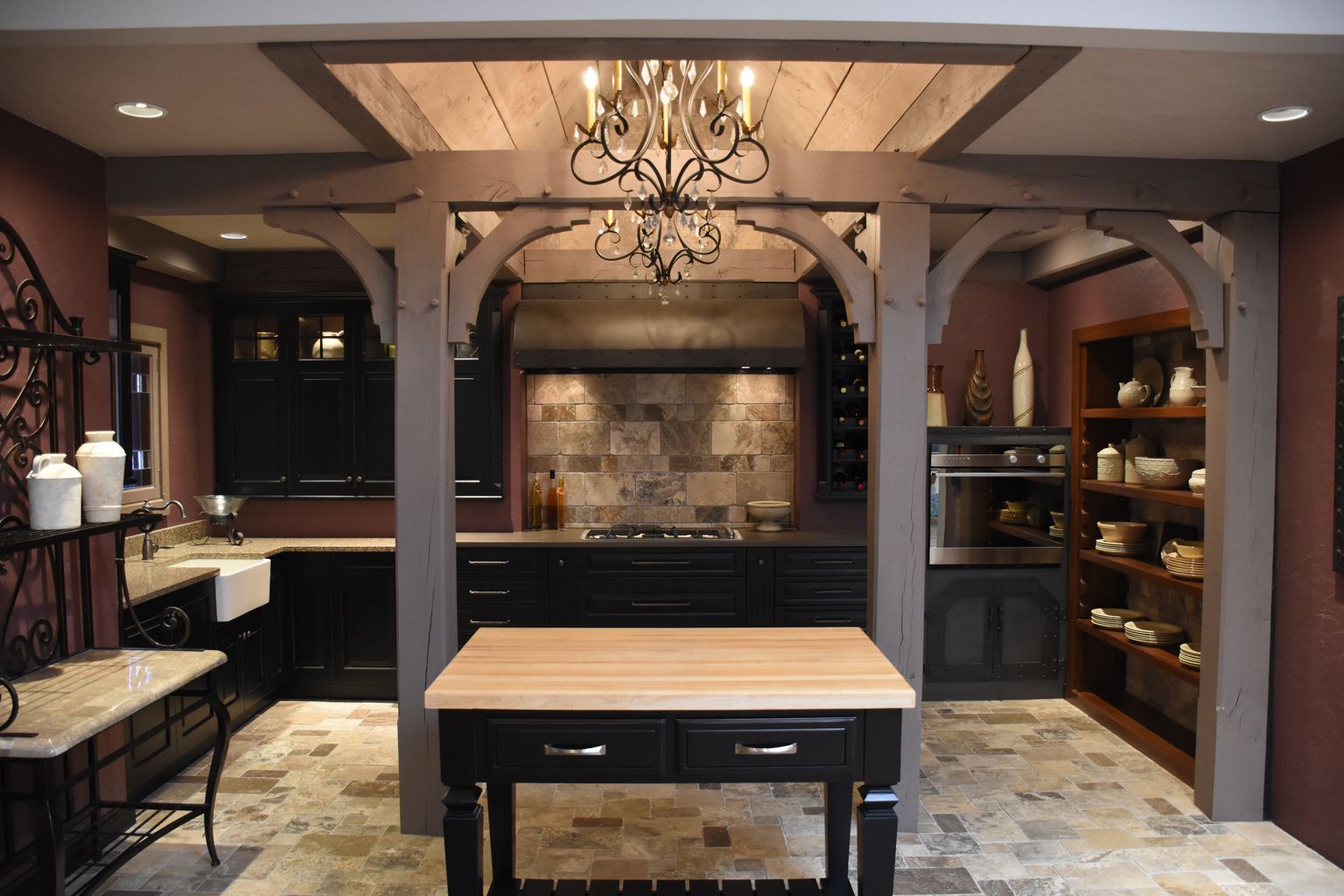 Elegant kitchen with wood island, stone backsplash, chandelier, and built-in shelves