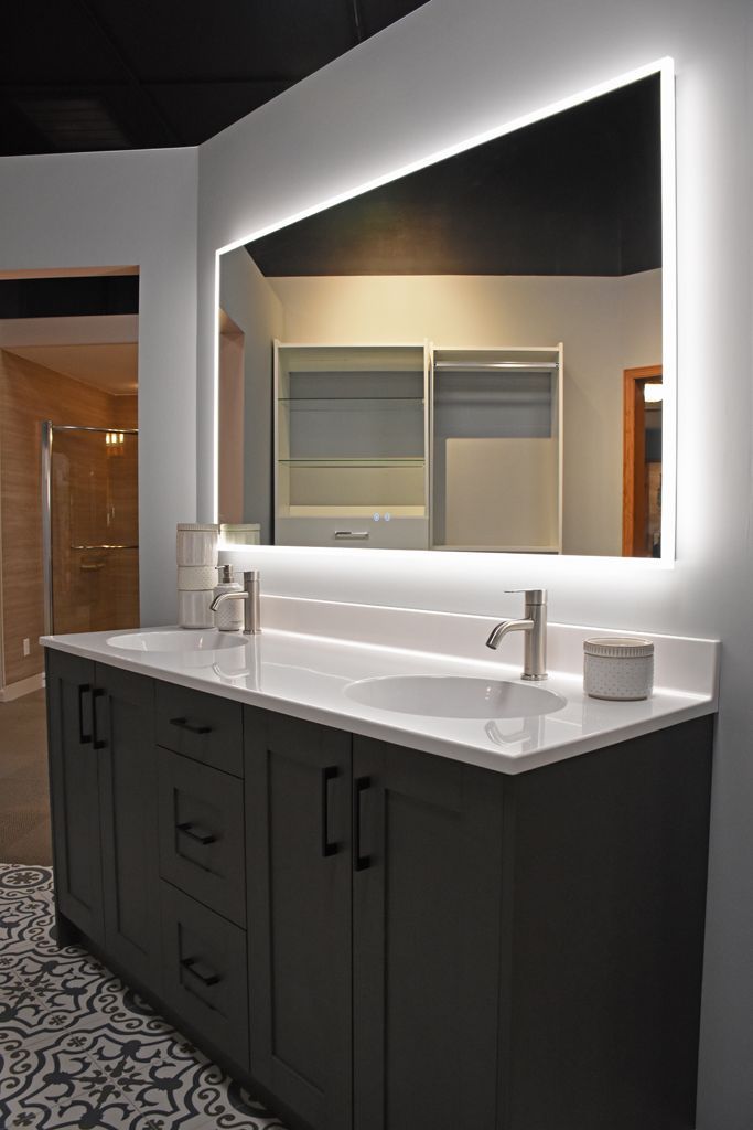 Modern bathroom vanity with double sinks, dark cabinets, large mirror, and bright lighting