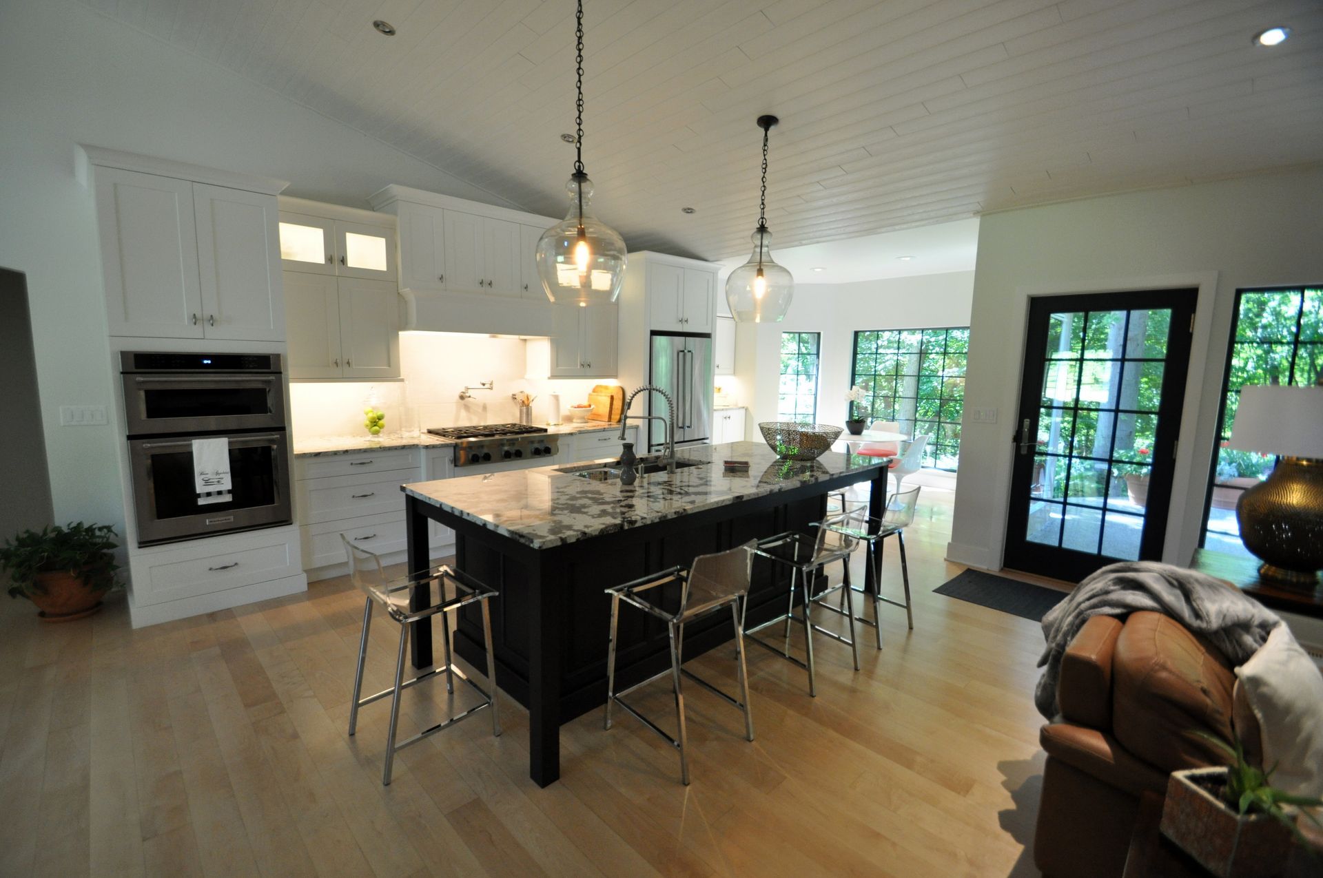 Bright modern kitchen with black island, pendant lights, and French doors to a patio